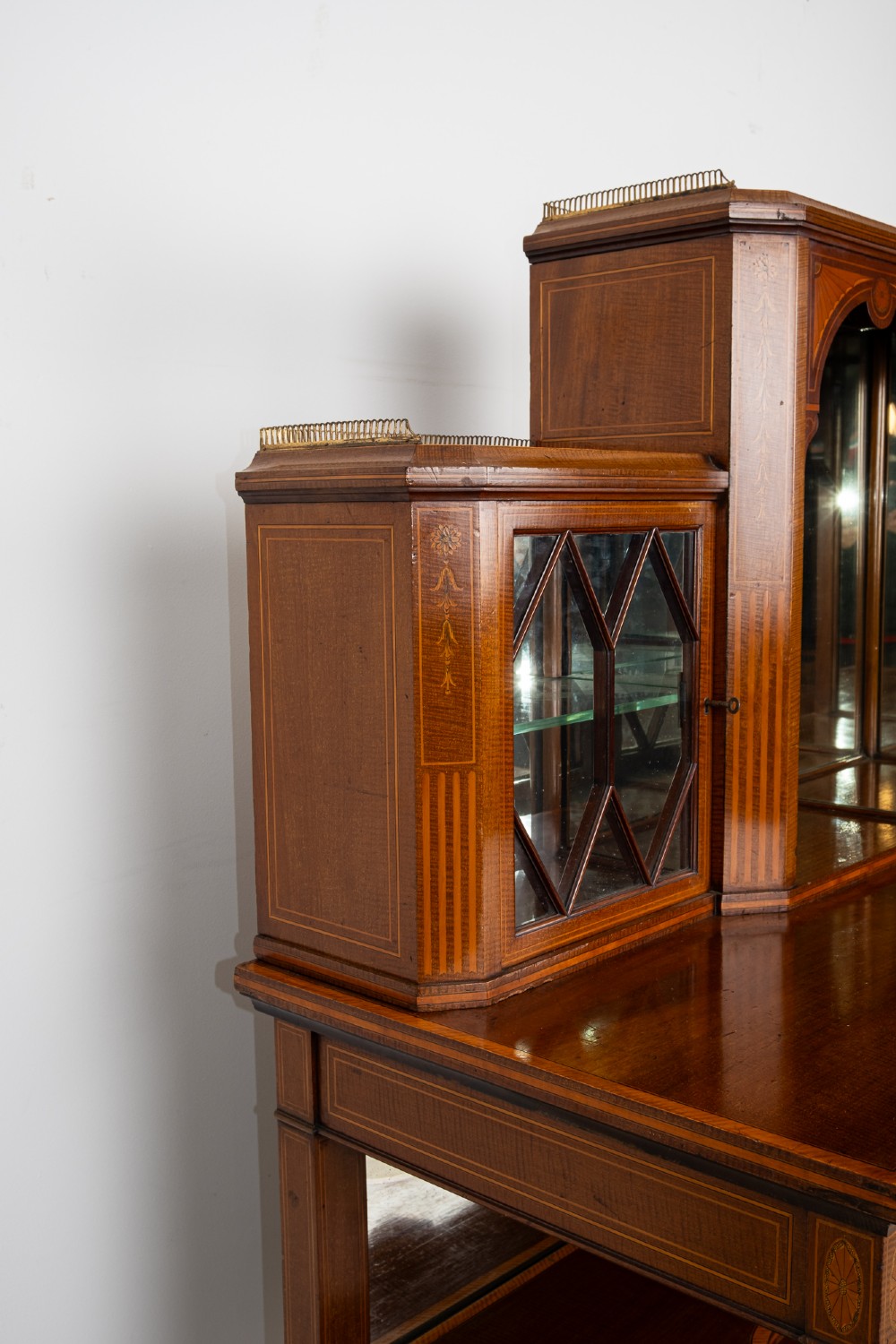 An Edwardian mahogany bonheur du jour writing desk featuring floral marquetry inlay, central mirrored recess, glazed side cabinets, and open lower shelves. View X