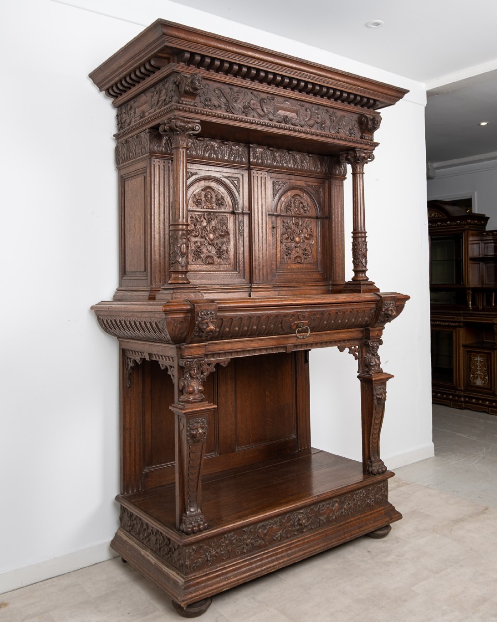A 19th-century carved oak buffet cupboard featuring intricate relief panels, architectural columns, an upper cabinet, and an open lower tier. View III