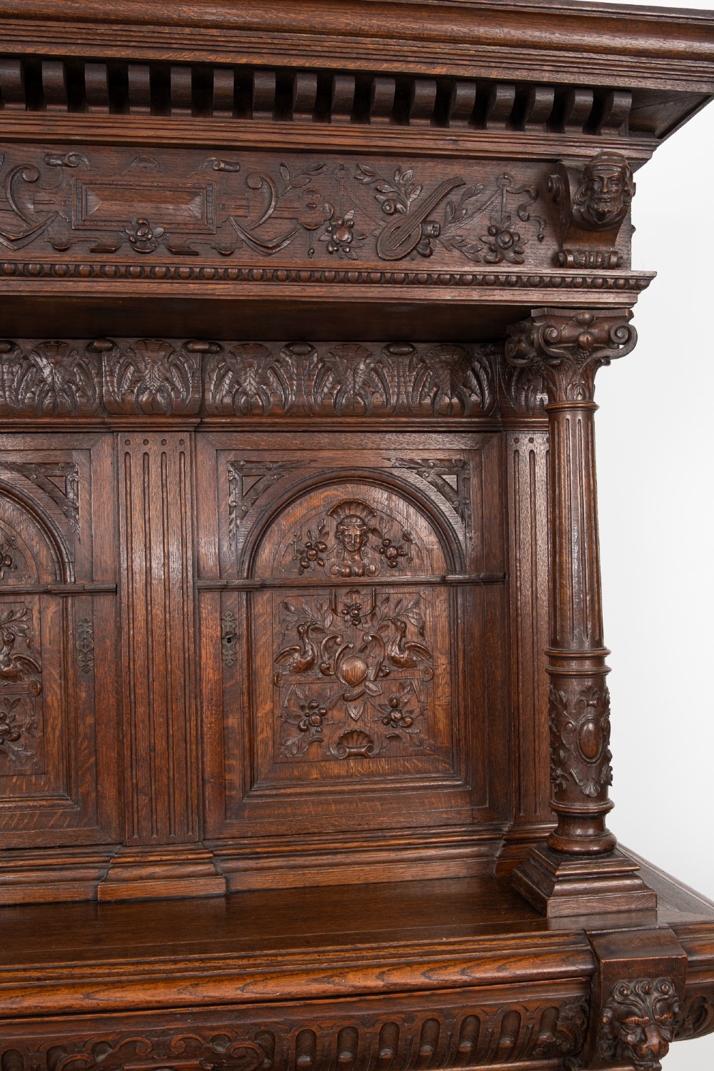 A 19th-century carved oak buffet cupboard featuring intricate relief panels, architectural columns, an upper cabinet, and an open lower tier. View VII