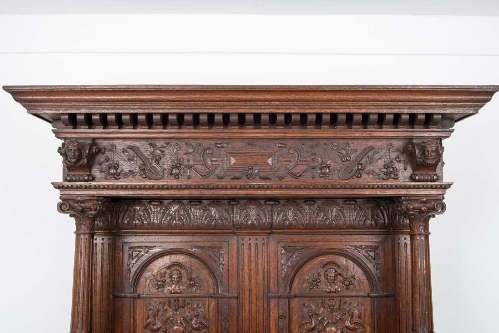A 19th-century carved oak buffet cupboard featuring intricate relief panels, architectural columns, an upper cabinet, and an open lower tier. View IX