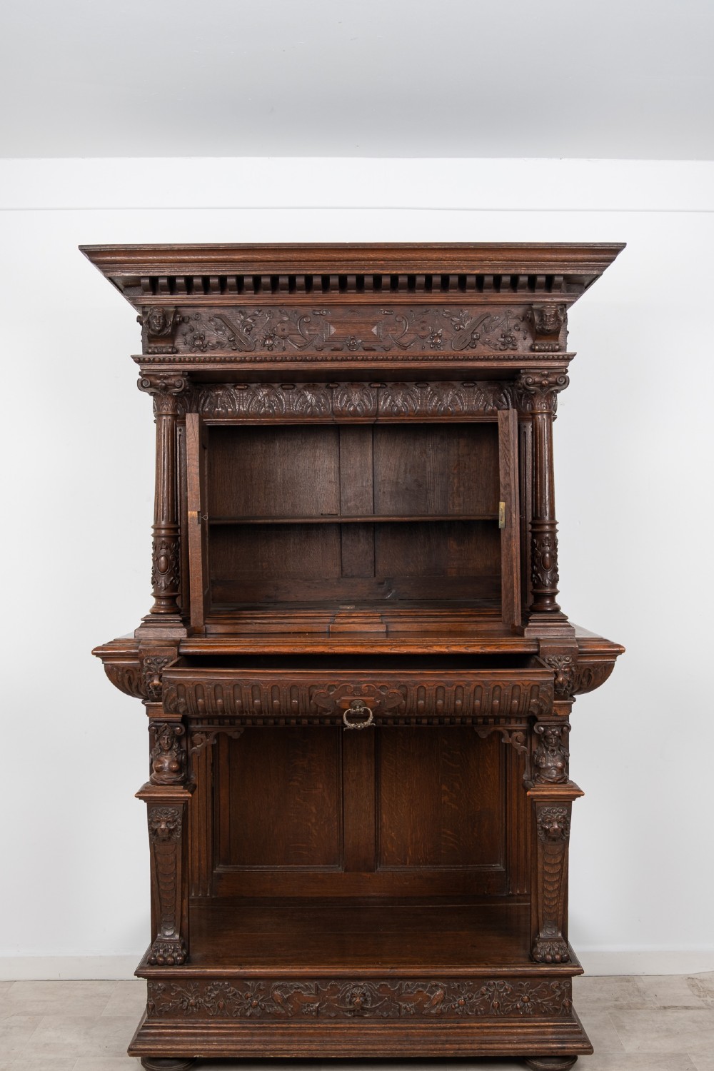 A 19th-century carved oak buffet cupboard featuring intricate relief panels, architectural columns, an upper cabinet, and an open lower tier. View X