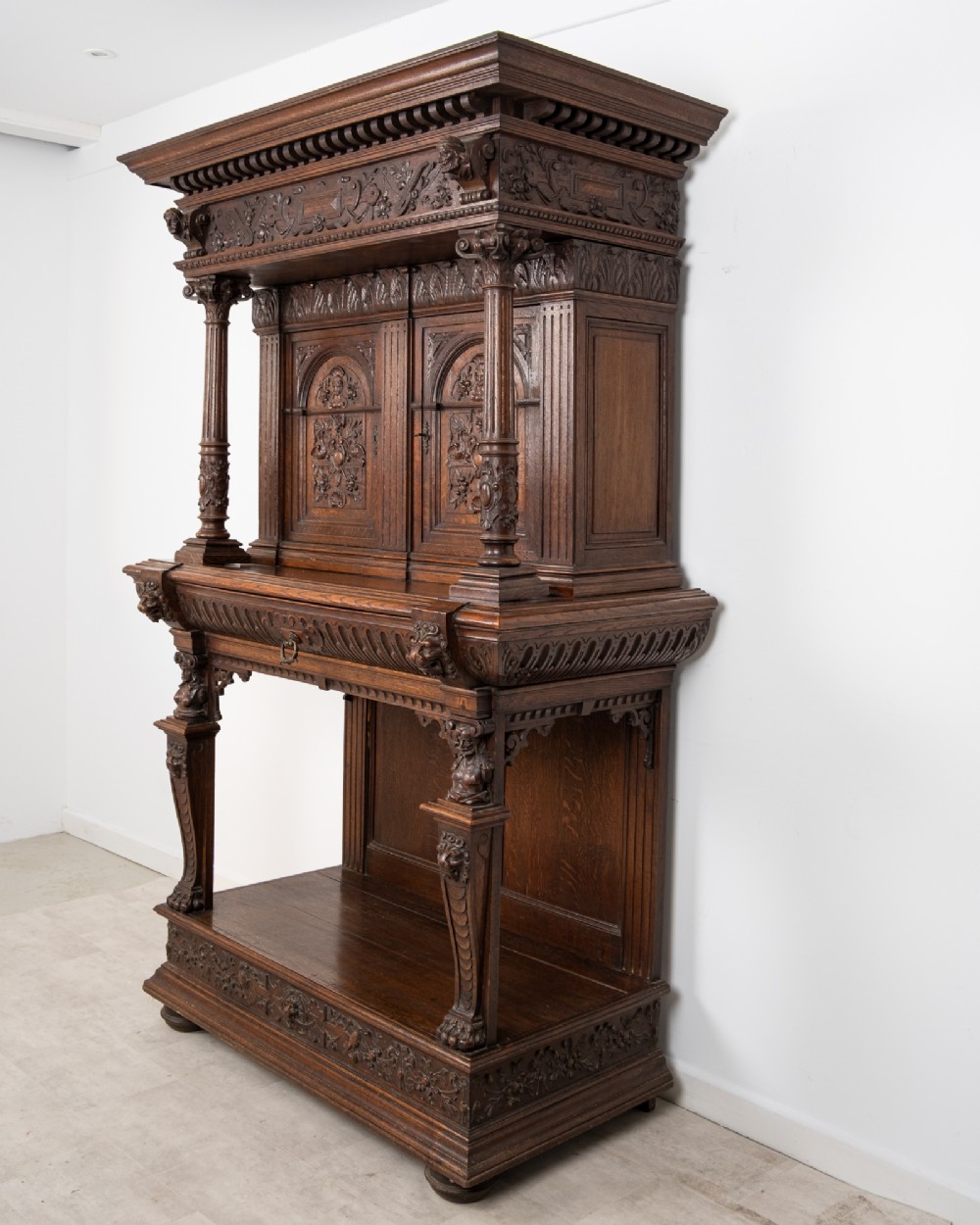 A 19th-century carved oak buffet cupboard featuring intricate relief panels, architectural columns, an upper cabinet, and an open lower tier. View XI