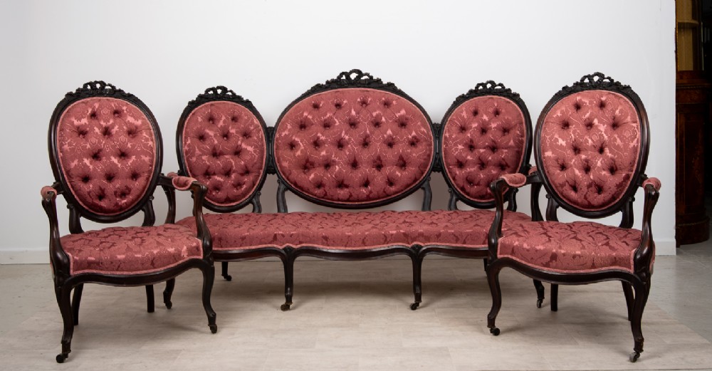 A three-piece Victorian mahogany salon suite featuring a three-back settee and two matching armchairs upholstered in rose-pink deep-buttoned fabric. View II