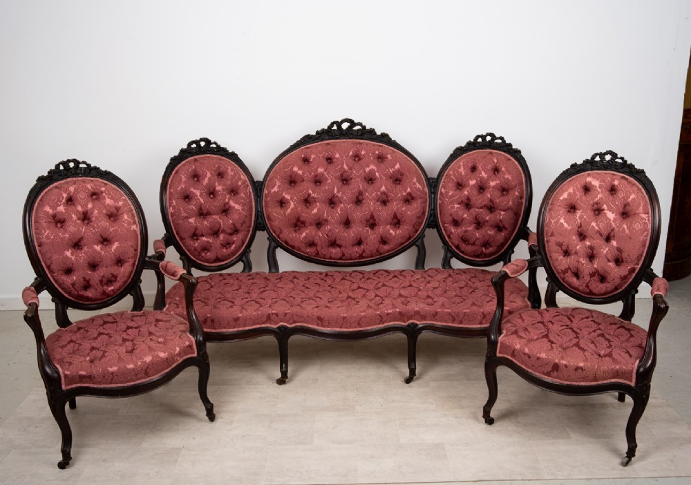 A three-piece Victorian mahogany salon suite featuring a three-back settee and two matching armchairs upholstered in rose-pink deep-buttoned fabric. View III