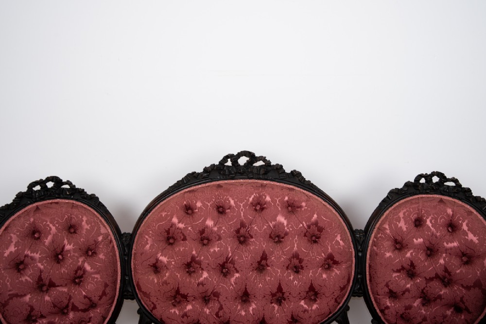 A three-piece Victorian mahogany salon suite featuring a three-back settee and two matching armchairs upholstered in rose-pink deep-buttoned fabric. View VI