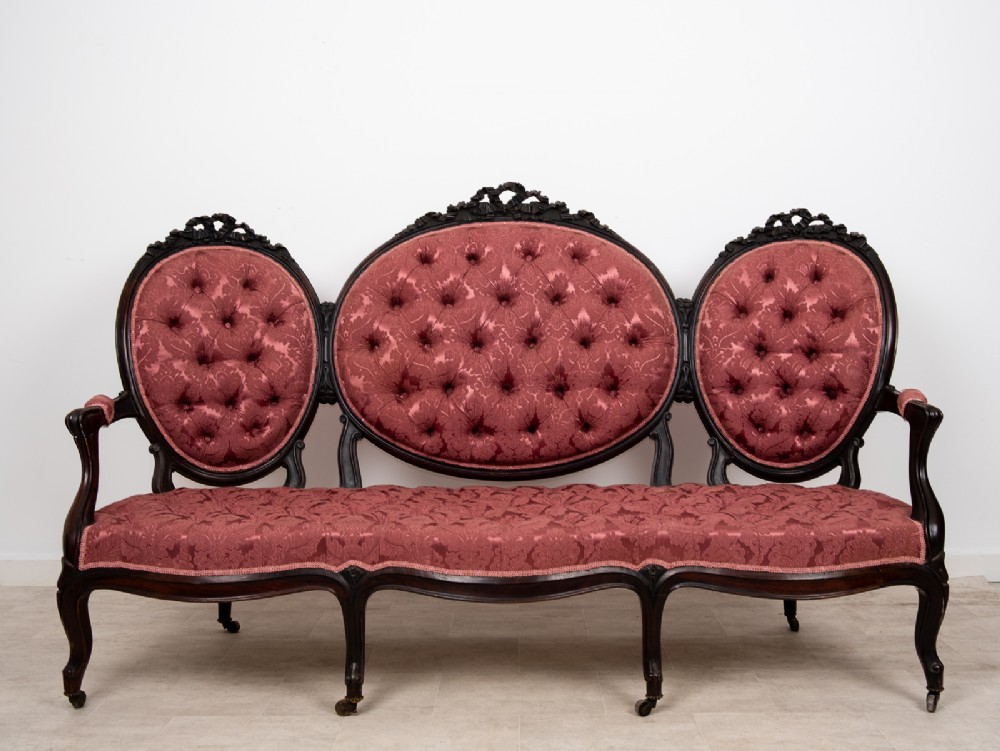 A three-piece Victorian mahogany salon suite featuring a three-back settee and two matching armchairs upholstered in rose-pink deep-buttoned fabric. View VIII