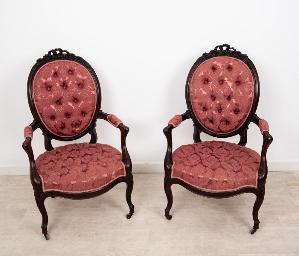 A three-piece Victorian mahogany salon suite featuring a three-back settee and two matching armchairs upholstered in rose-pink deep-buttoned fabric. View X