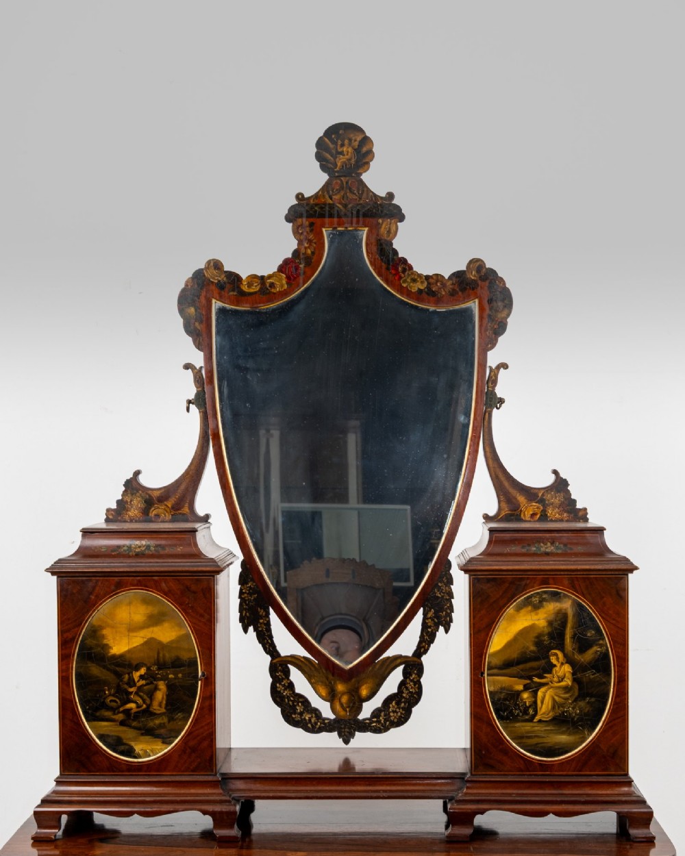 An Edwardian mahogany tabletop toilet mirror with a central shield-shaped swing glass flanked by two small painted cabinet pedestals.