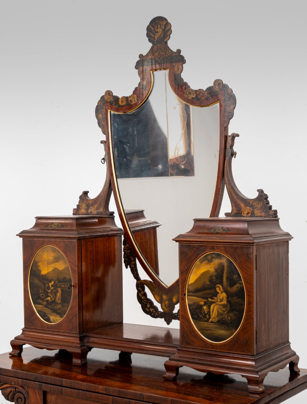An Edwardian mahogany tabletop toilet mirror with a central shield-shaped swing glass flanked by two small painted cabinet pedestals. View II