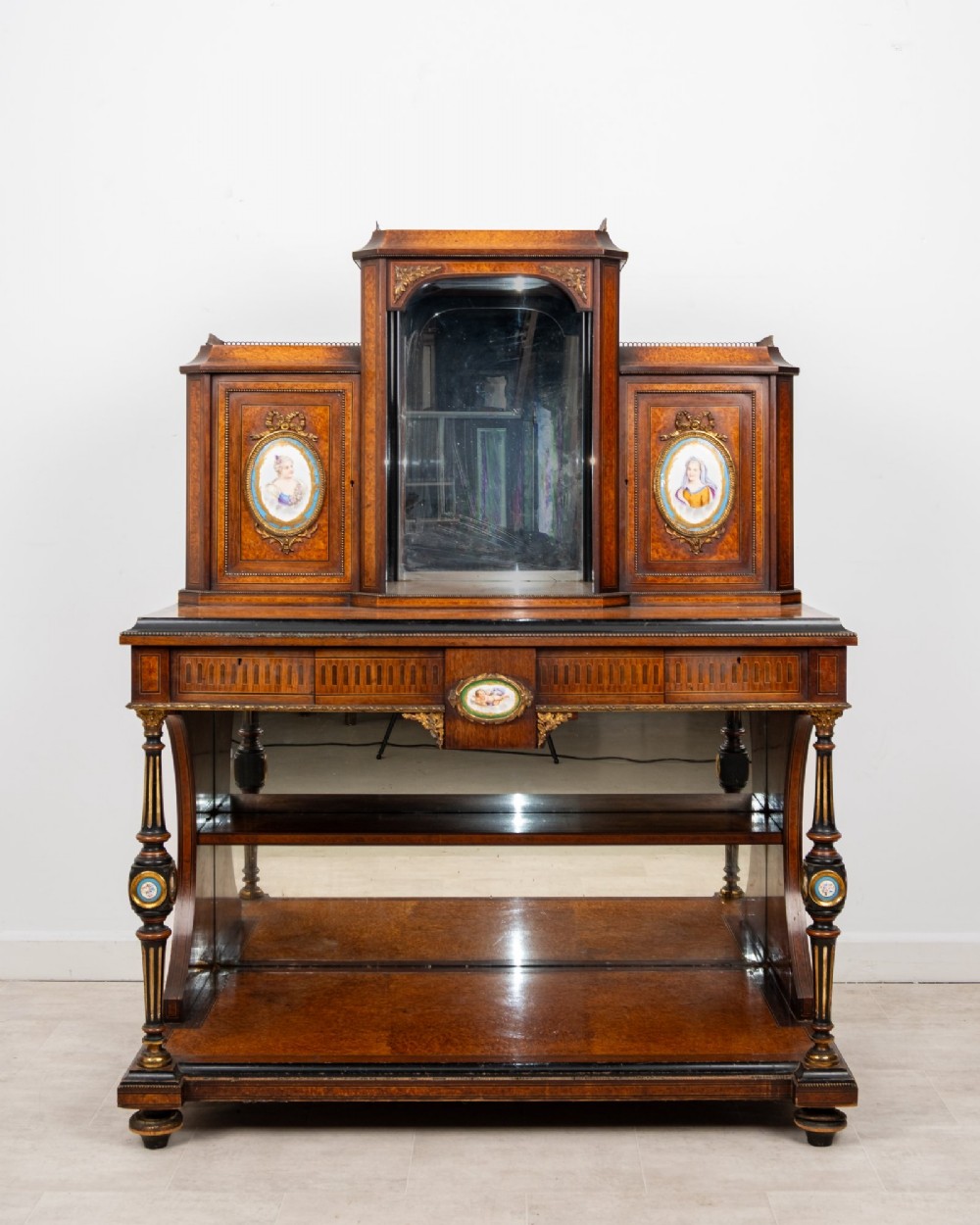 An antique French amboyna and ebonised bonheur du jour writing desk featuring inset porcelain plaques, gilt metal mounts, a central mirrored superstructure, and lower tier shelving. View II