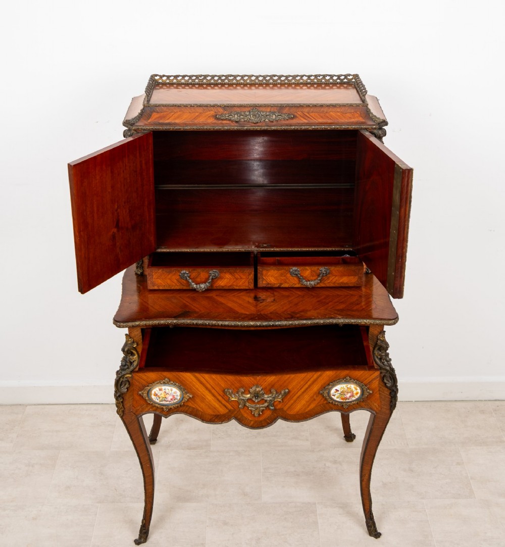 An antique French kingwood bonheur du jour writing desk featuring an upper cabinet with porcelain plaques, ornate ormolu mounts, and slender cabriole legs. View VIII