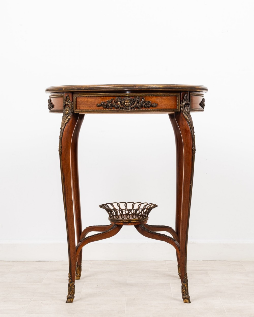 A circular French kingwood centre table featuring parquetry top inlay, gilt-bronze mounts, cabriole legs, and a central undertier basket. View II