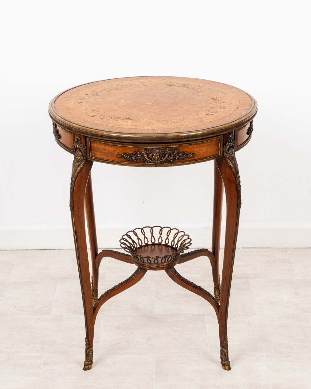 A circular French kingwood centre table featuring parquetry top inlay, gilt-bronze mounts, cabriole legs, and a central undertier basket. View III