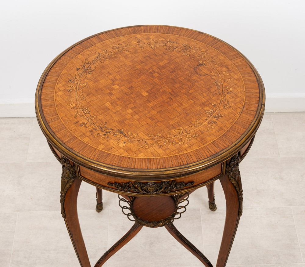 A circular French kingwood centre table featuring parquetry top inlay, gilt-bronze mounts, cabriole legs, and a central undertier basket. View IV
