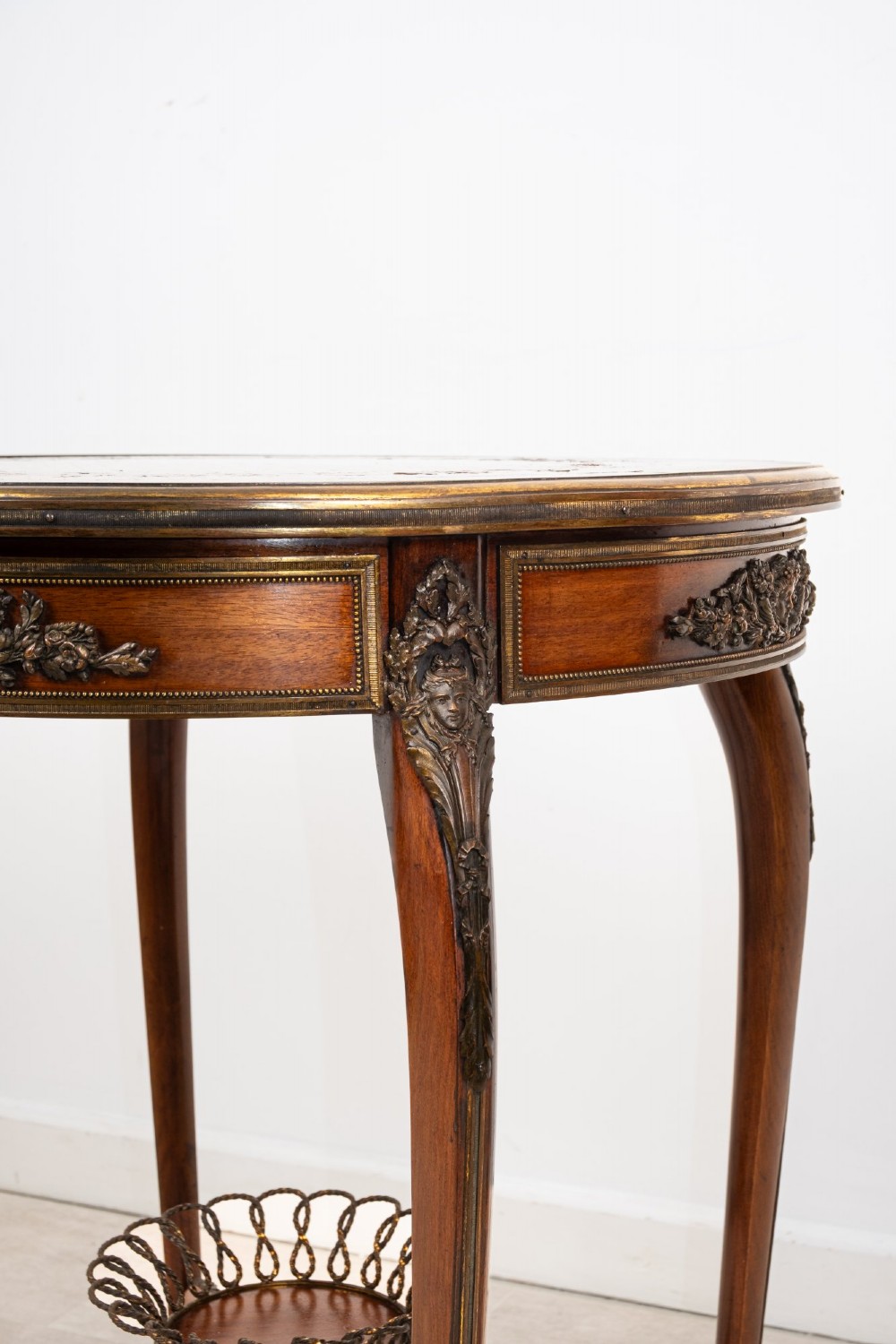 A circular French kingwood centre table featuring parquetry top inlay, gilt-bronze mounts, cabriole legs, and a central undertier basket. View VI