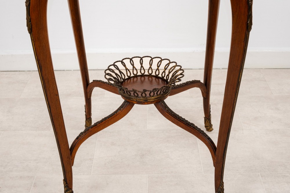 A circular French kingwood centre table featuring parquetry top inlay, gilt-bronze mounts, cabriole legs, and a central undertier basket. View VII