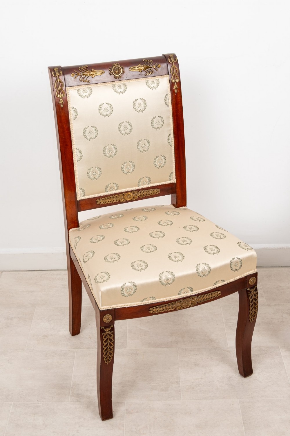 A pair of late 19th-century French Empire Revival mahogany side chairs featuring gilt-bronze ormolu mounts and cream upholstered seats and backrests. View II