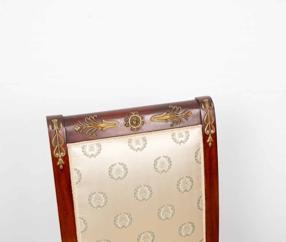 A pair of late 19th-century French Empire Revival mahogany side chairs featuring gilt-bronze ormolu mounts and cream upholstered seats and backrests. View IV