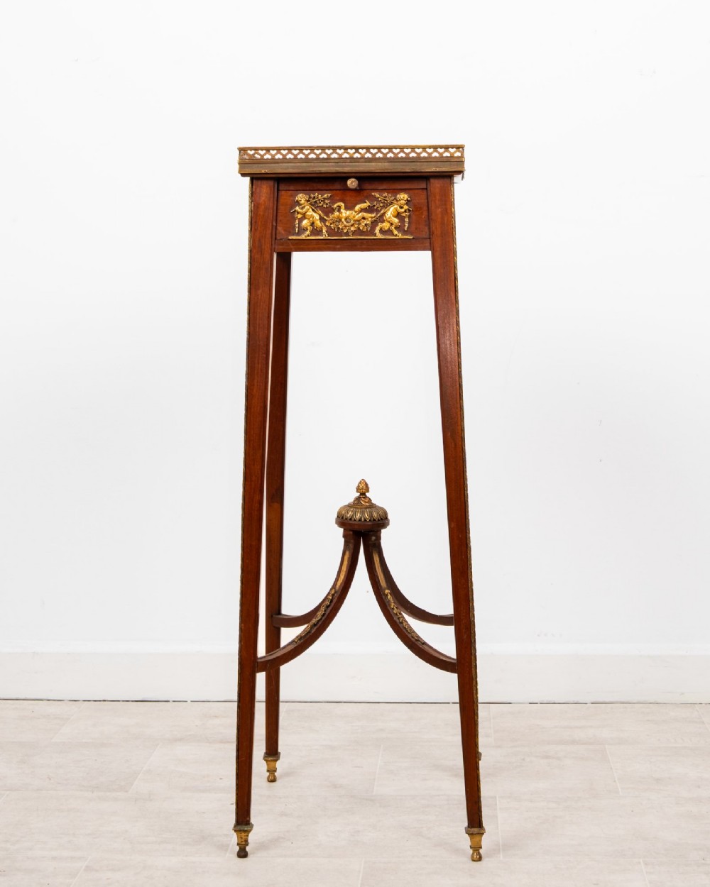 A tall French mahogany side table featuring a square rouge marble top with a pierced brass gallery, gilt-bronze frieze reliefs, and slender tapered legs connected by a curved stretcher. View II