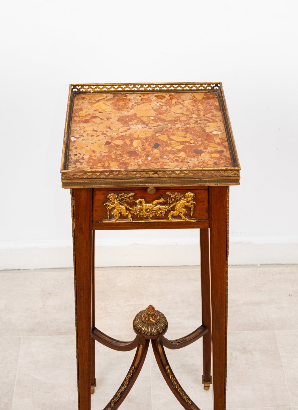 A tall French mahogany side table featuring a square rouge marble top with a pierced brass gallery, gilt-bronze frieze reliefs, and slender tapered legs connected by a curved stretcher. View IV