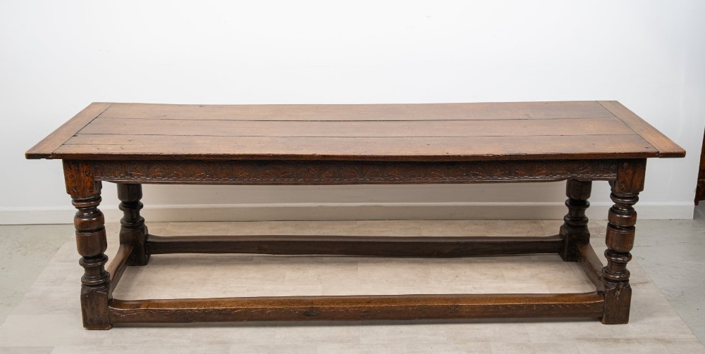 An 18th century carved oak refectory dining table featuring turned legs, a carved frieze apron, and low perimeter stretchers. View III