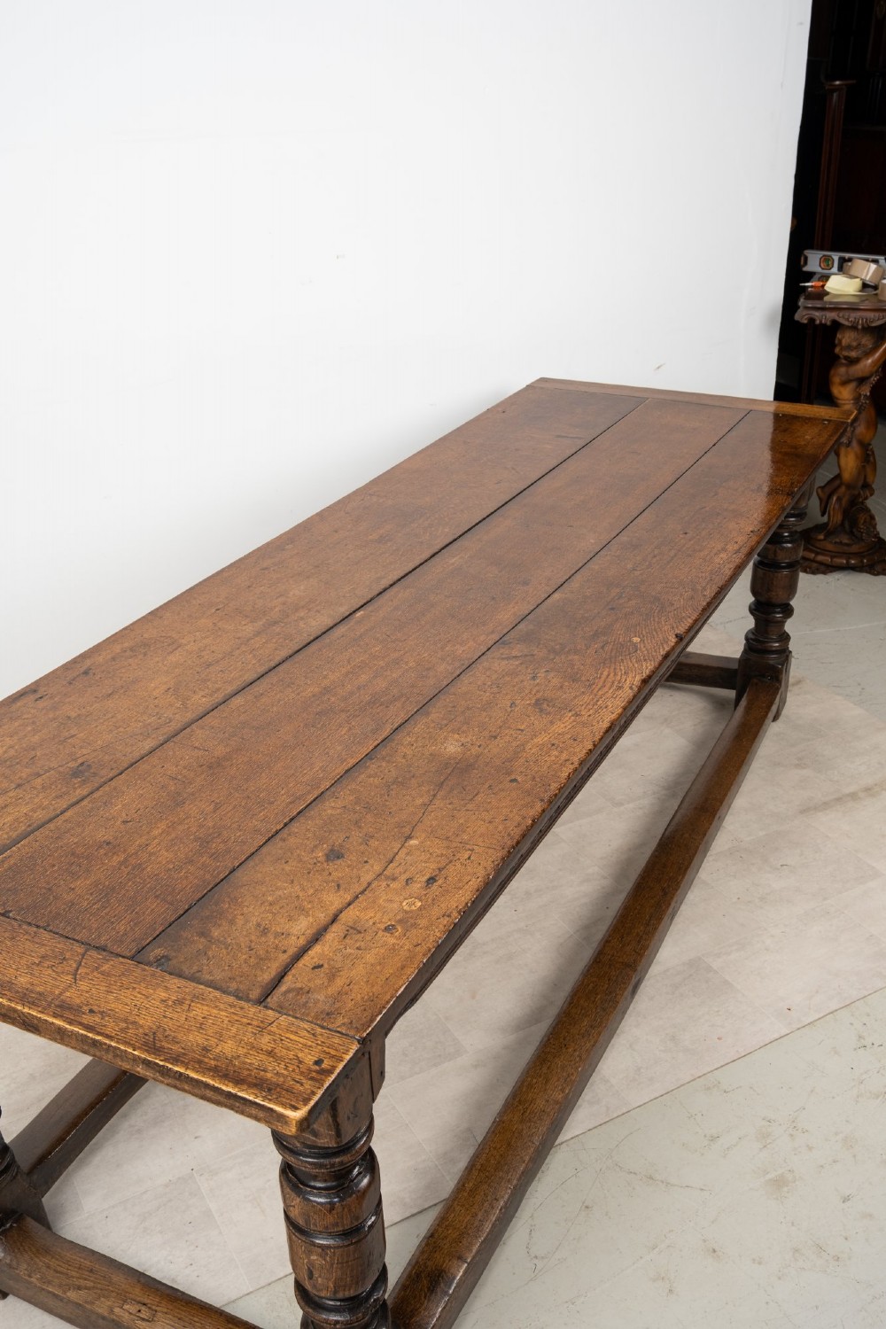 An 18th century carved oak refectory dining table featuring turned legs, a carved frieze apron, and low perimeter stretchers. View VIII