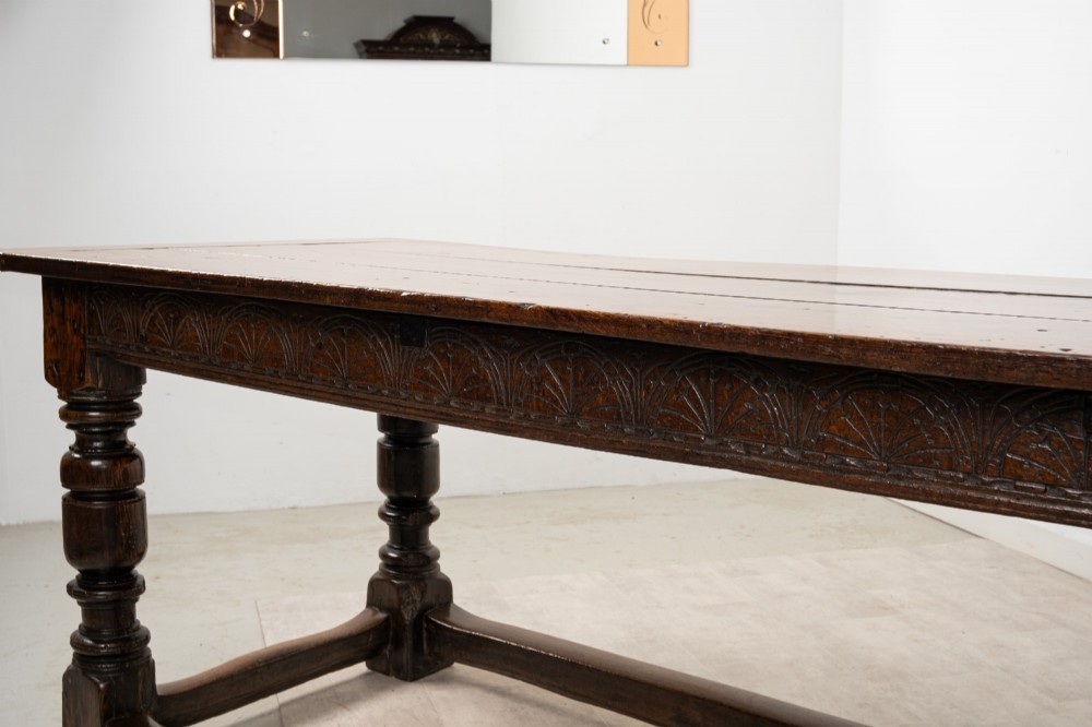 An 18th century carved oak refectory dining table featuring turned legs, a carved frieze apron, and low perimeter stretchers. View XI