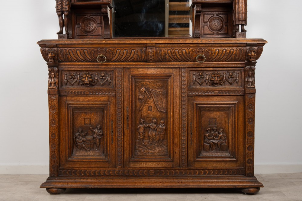 A late Victorian dark carved oak mirror-back sideboard featuring carved figural columns, relief panels, and a upper display shelf. View IV
