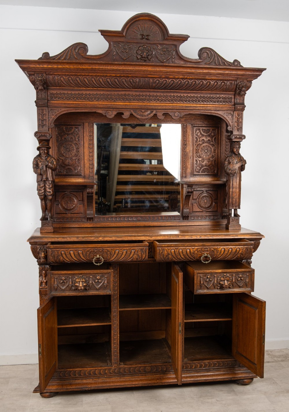 A late Victorian dark carved oak mirror-back sideboard featuring carved figural columns, relief panels, and a upper display shelf. View IX