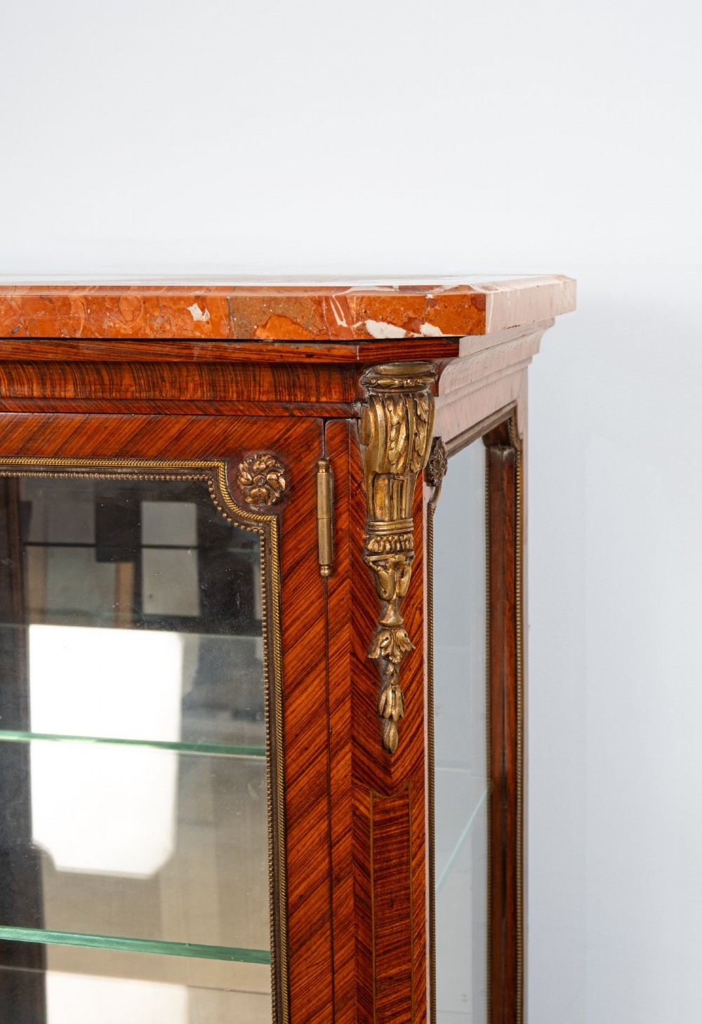 An antique French Louis XV style kingwood vitrine cabinet featuring a single glazed door, gilt-bronze mounts, a mirrored back interior, glass shelves, and a marble top. View V