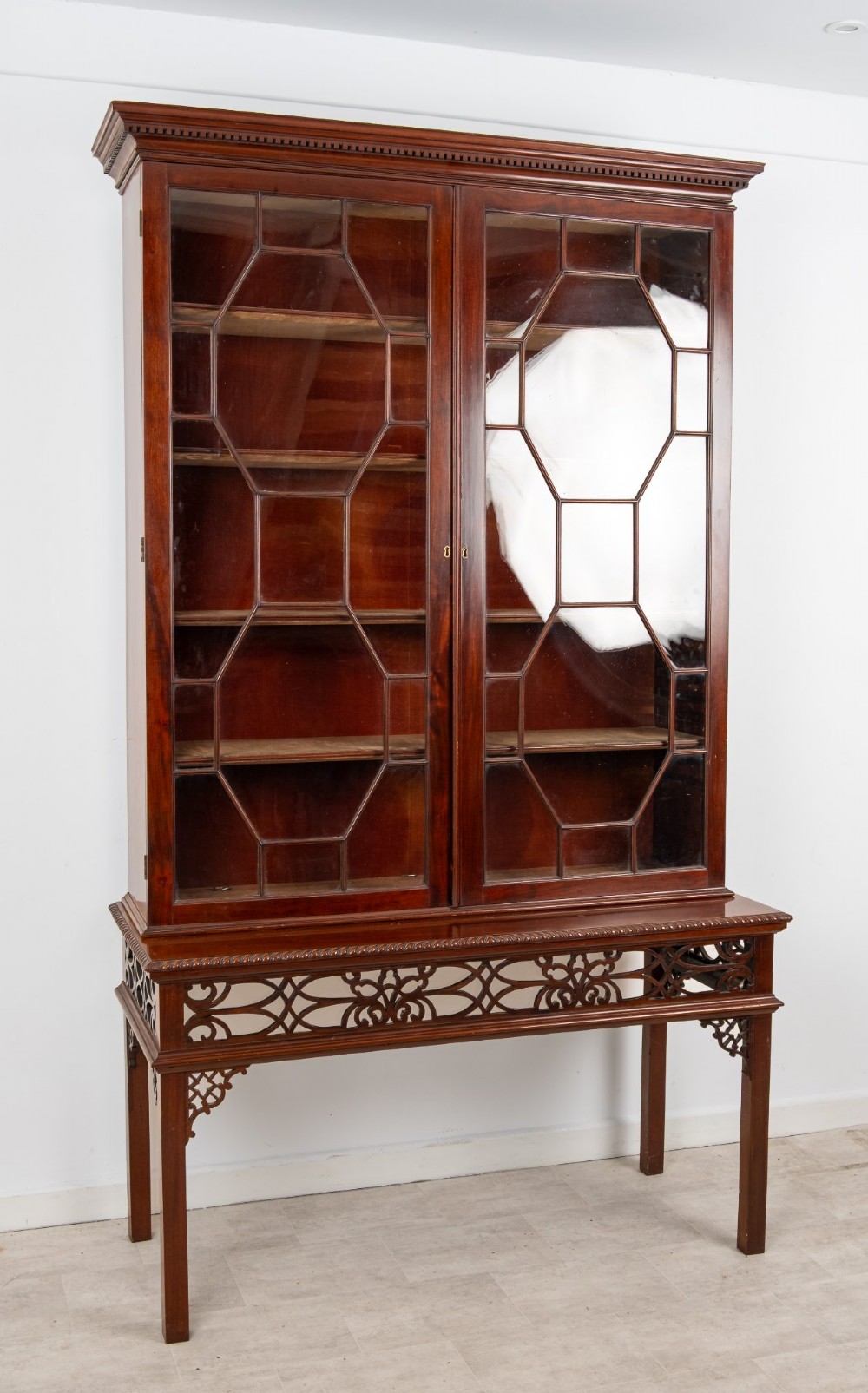 An antique mahogany astragal glazed bookcase resting on a carved matching stand with fretwork detailing. View III