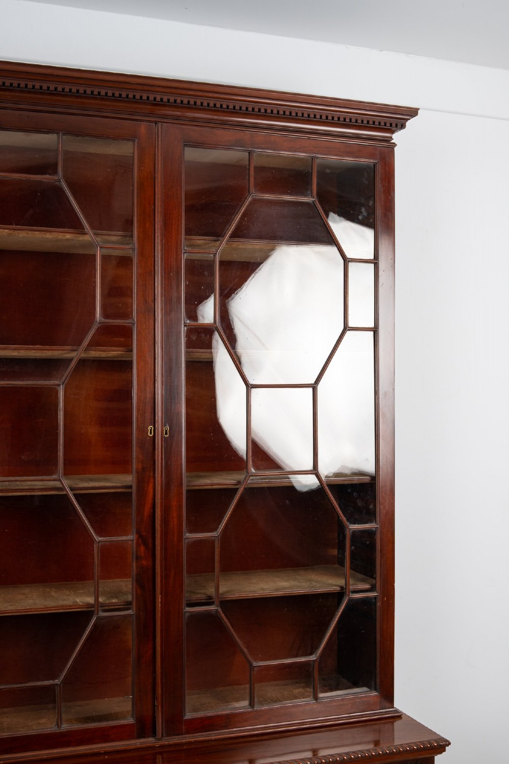 An antique mahogany astragal glazed bookcase resting on a carved matching stand with fretwork detailing. View V