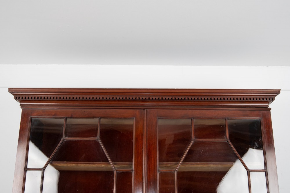 An antique mahogany astragal glazed bookcase resting on a carved matching stand with fretwork detailing. View VI