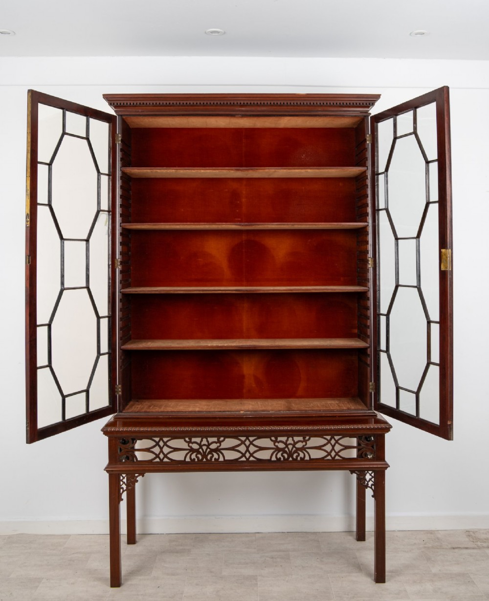 An antique mahogany astragal glazed bookcase resting on a carved matching stand with fretwork detailing. View VIII