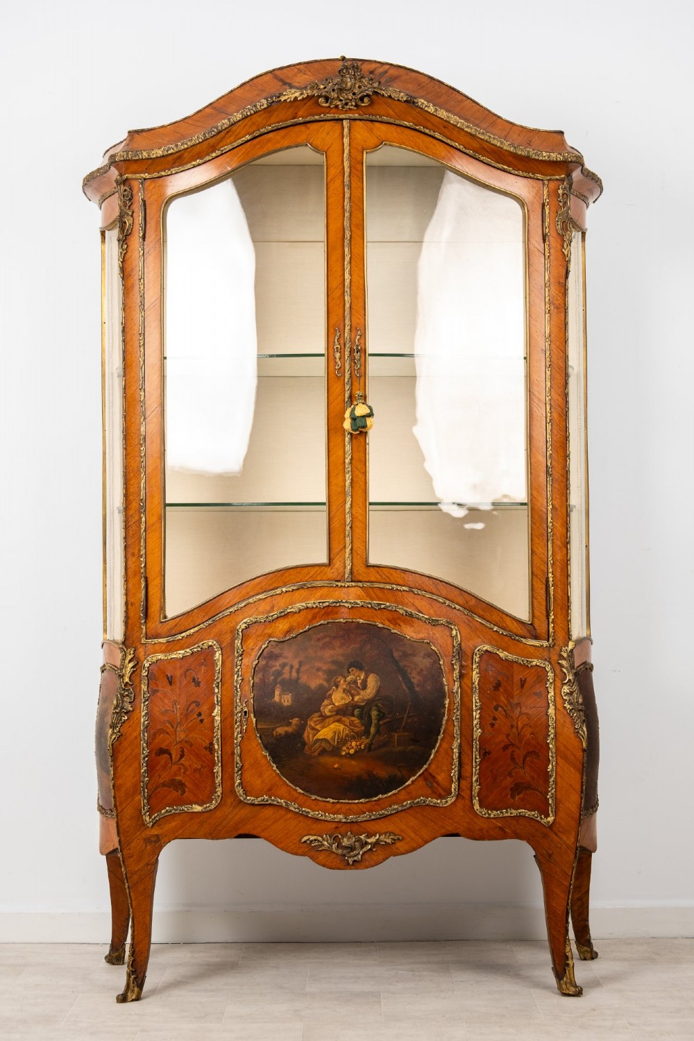 An antique French Louis XV style kingwood vitrine cabinet featuring glass doors, gilded ormolu mounts, and a hand-painted Vernis Martin panel at the base.