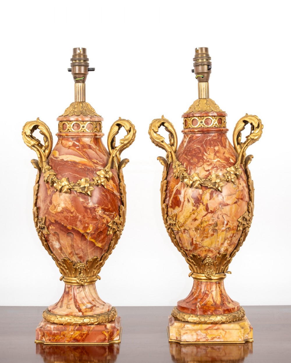 A pair of late nineteenth-century French urn-form table lamps crafted from veined red marble with gilt bronze scroll handles and floral garlands. View II