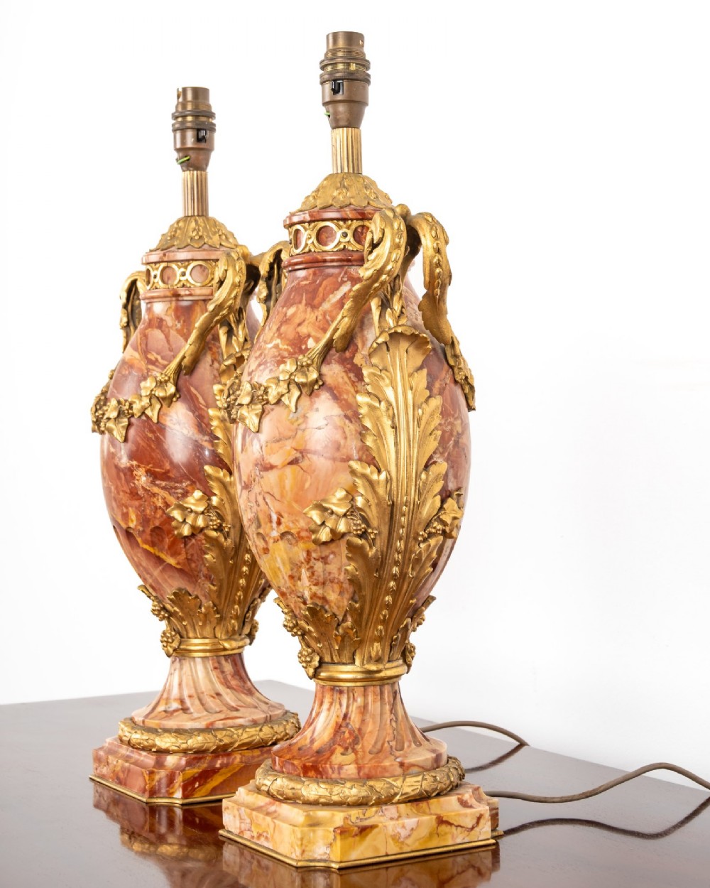A pair of late nineteenth-century French urn-form table lamps crafted from veined red marble with gilt bronze scroll handles and floral garlands. View IV