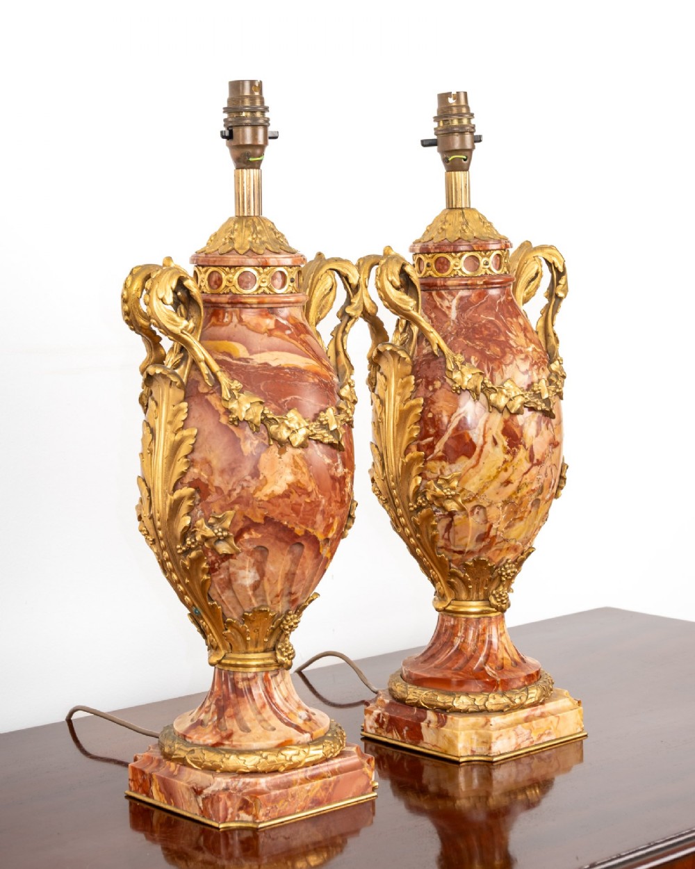 A pair of late nineteenth-century French urn-form table lamps crafted from veined red marble with gilt bronze scroll handles and floral garlands. View X