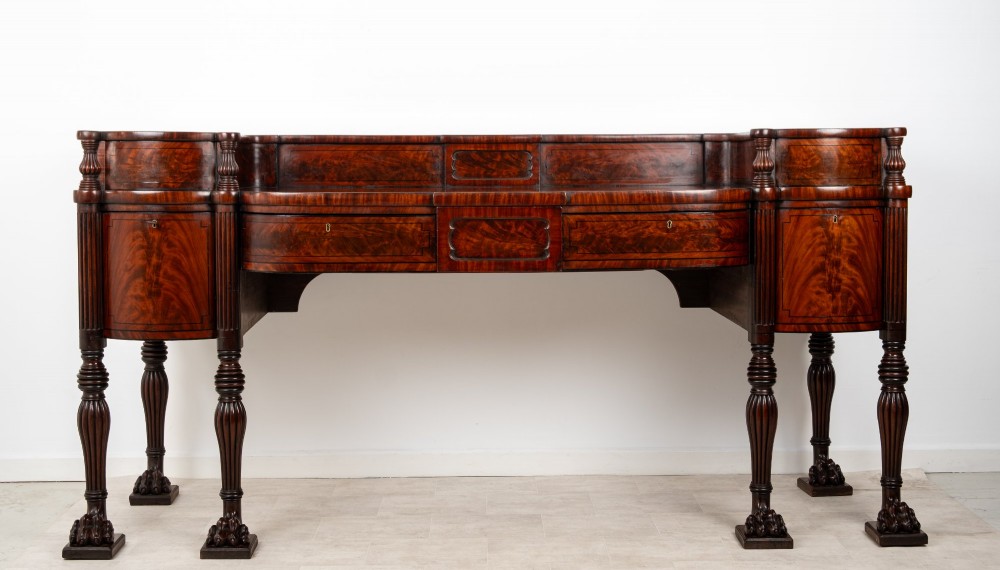 A Regency flame mahogany sideboard featuring reeded turned legs, carved paw feet, multiple storage drawers, and a raised back gallery rail. View III