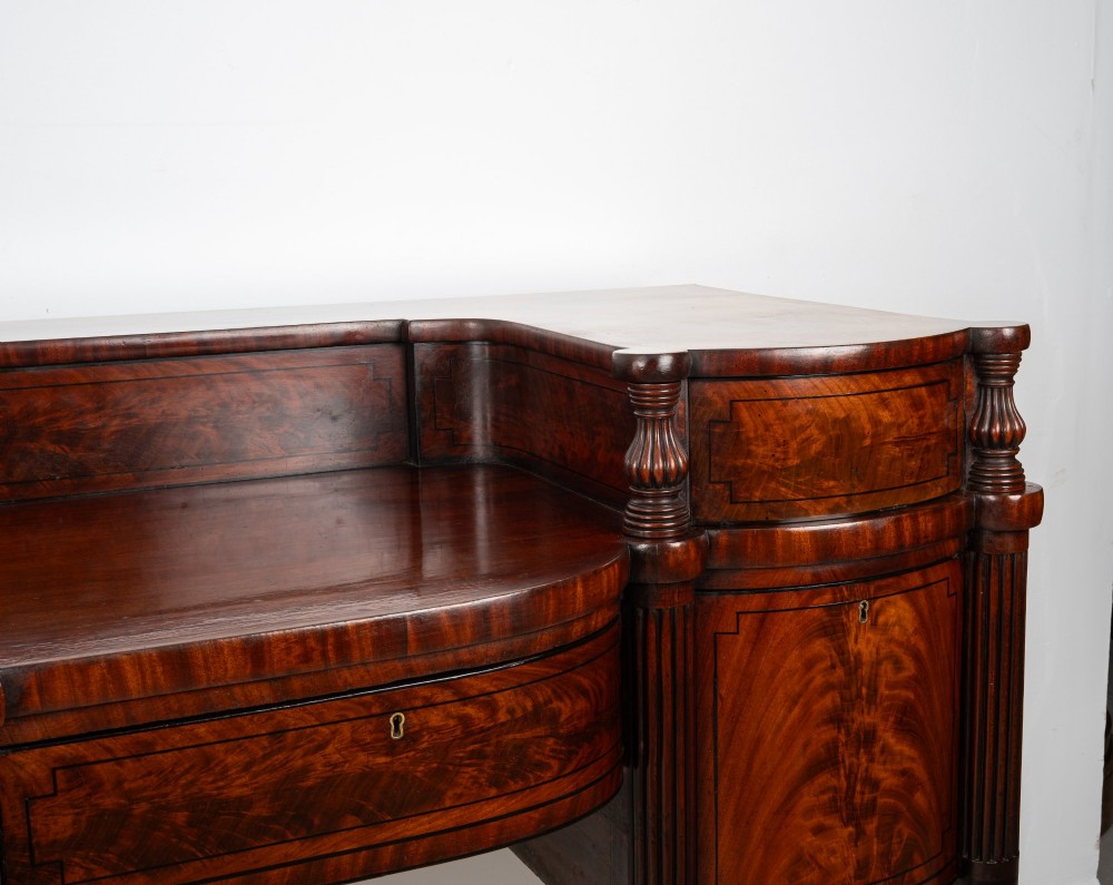 A Regency flame mahogany sideboard featuring reeded turned legs, carved paw feet, multiple storage drawers, and a raised back gallery rail. View VII