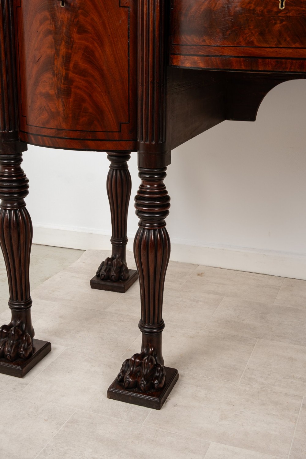 A Regency flame mahogany sideboard featuring reeded turned legs, carved paw feet, multiple storage drawers, and a raised back gallery rail. View VIII