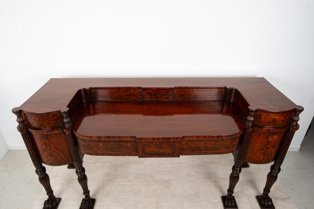 A Regency flame mahogany sideboard featuring reeded turned legs, carved paw feet, multiple storage drawers, and a raised back gallery rail. View XIII