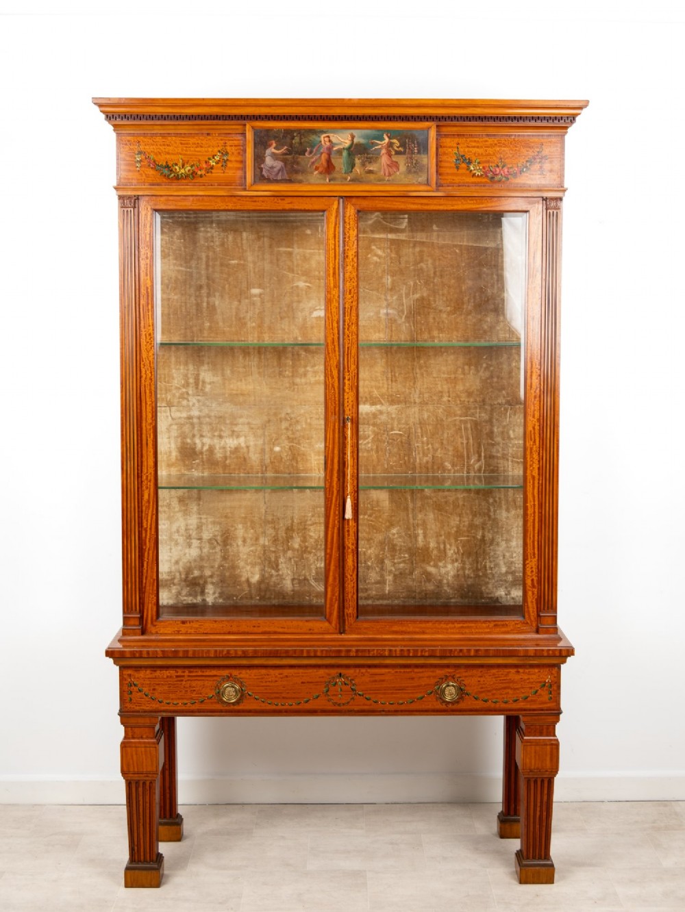 An Edwardian satinwood display cabinet on stand featuring glazed double doors, hand-painted floral garlands, and a central classical figural panel. View III