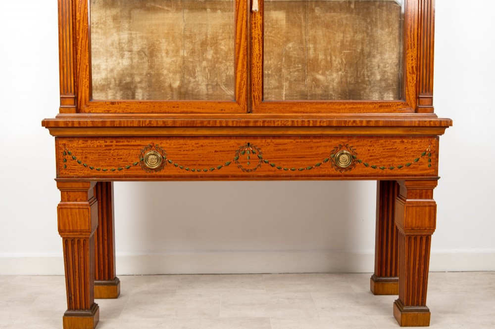 An Edwardian satinwood display cabinet on stand featuring glazed double doors, hand-painted floral garlands, and a central classical figural panel. View V