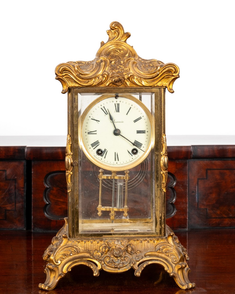 A late 19th-century Rococo Revival gilt bronze crystal regulator mantel clock featuring four bevelled glass panels, ornate scrollwork casting, an enamel dial with Roman numerals, and a visible mercury-style pendulum. View III