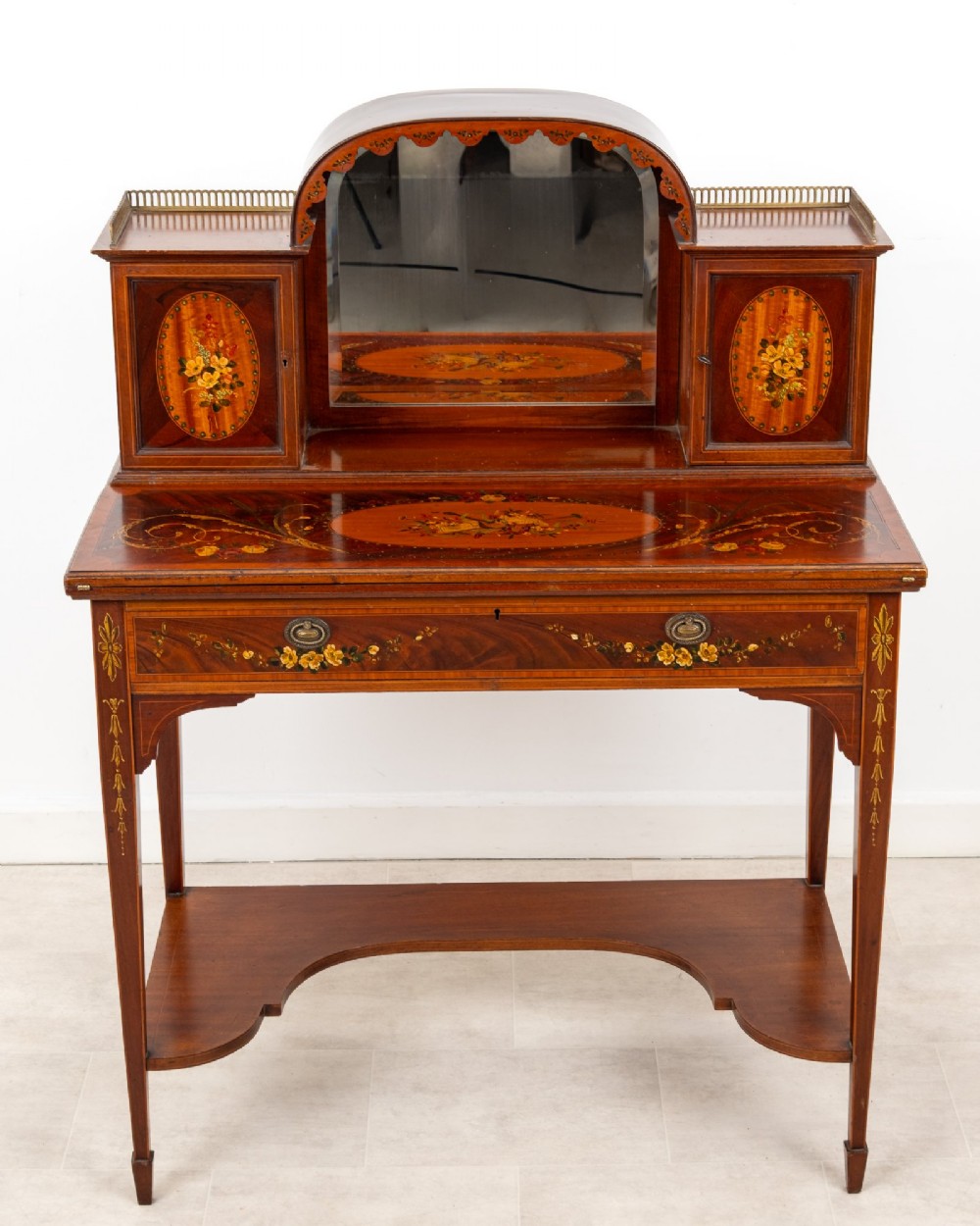 An Edwardian mahogany writing desk featuring floral hand-painted motifs, twin upper cabinets with brass galleries, an arched central mirror, and a single frieze drawer. View III