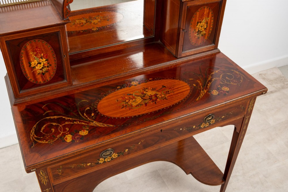 An Edwardian mahogany writing desk featuring floral hand-painted motifs, twin upper cabinets with brass galleries, an arched central mirror, and a single frieze drawer. View VII
