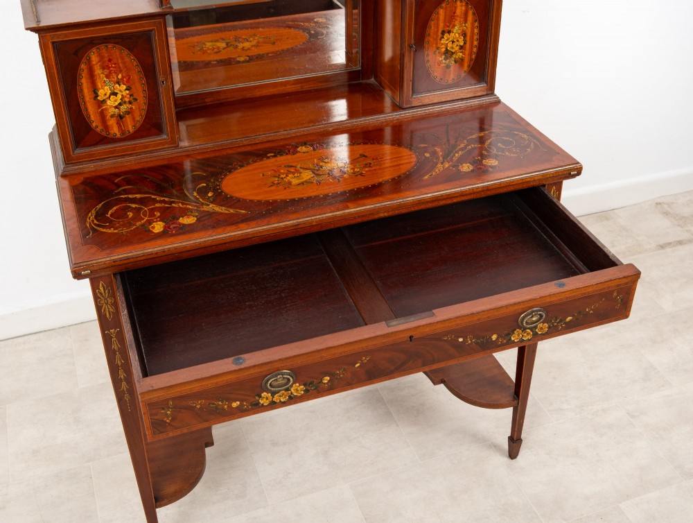 An Edwardian mahogany writing desk featuring floral hand-painted motifs, twin upper cabinets with brass galleries, an arched central mirror, and a single frieze drawer. View XI