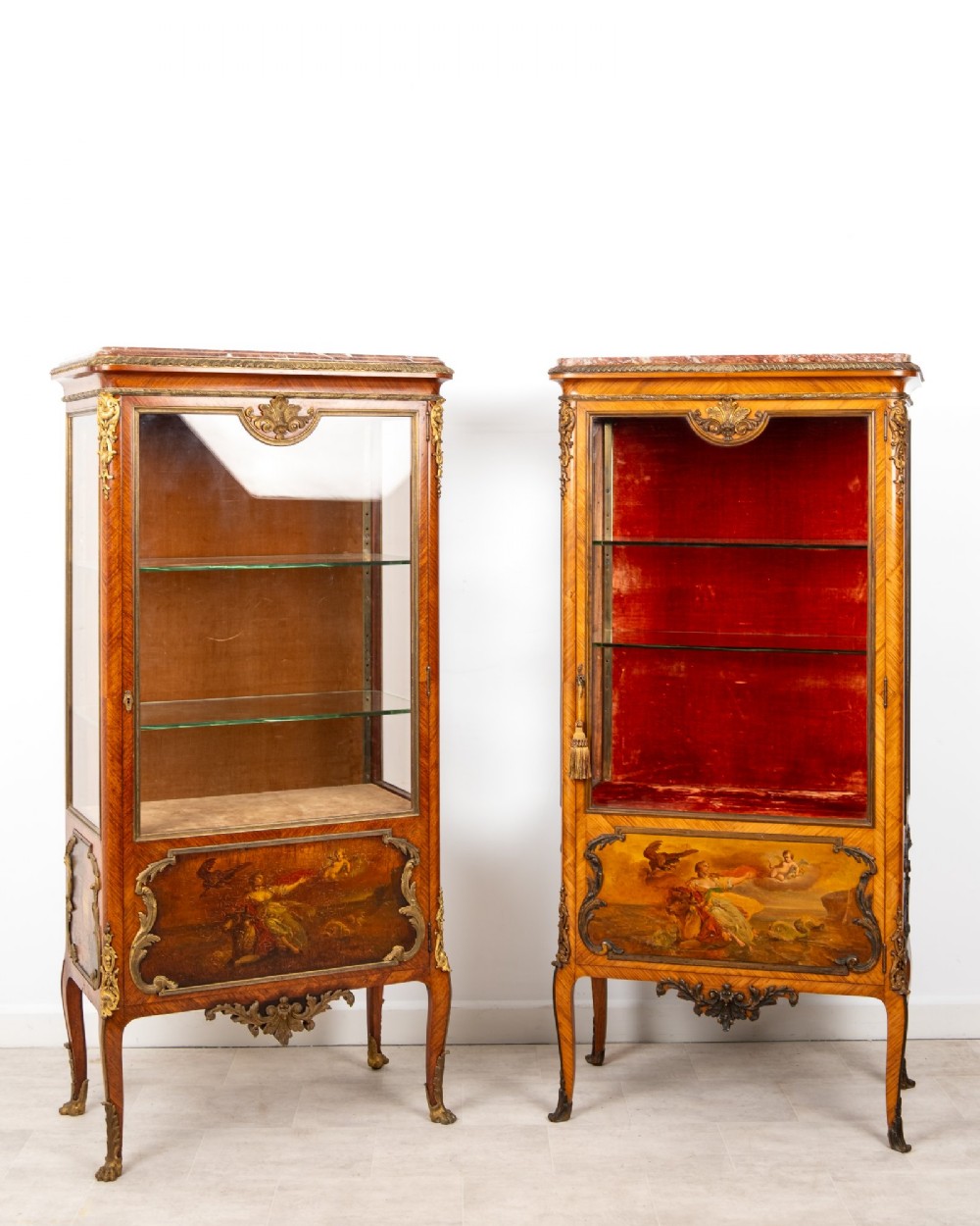 Pair of late 19th-century French kingwood vitrine cabinets featuring marble tops, glass display sections, hand-painted lower panels, and decorative gilt bronze mounts.