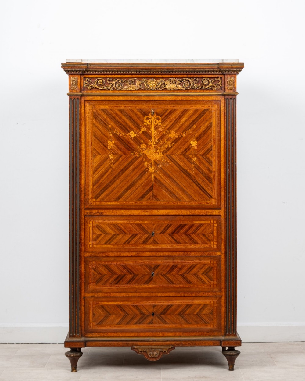 An antique nineteenth-century French parquetry secretaire a abattant writing desk featuring geometric veneer patterns, floral marquetry, gilt bronze mounts, and a marble top.